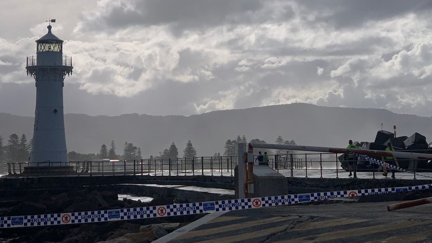 Break wall of harbour with police tape in foreground and light house in back ground