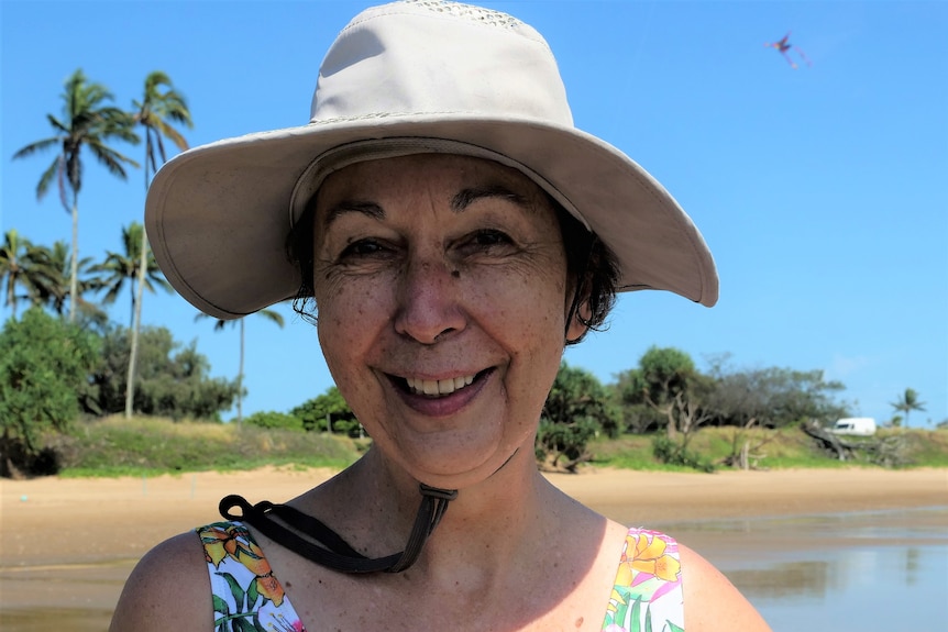 Close up photo of an elderly woman with brown eyes, wearing a sun hat. 