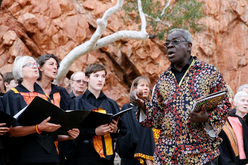 A conductor leads a choir, choir sings in background