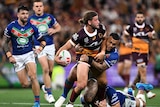 A Brisbane Broncos NRL player offloads in the tackle against the Warriors.