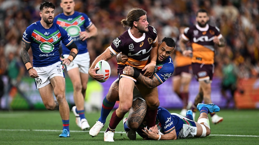 A Brisbane Broncos NRL player offloads in the tackle against the Warriors.