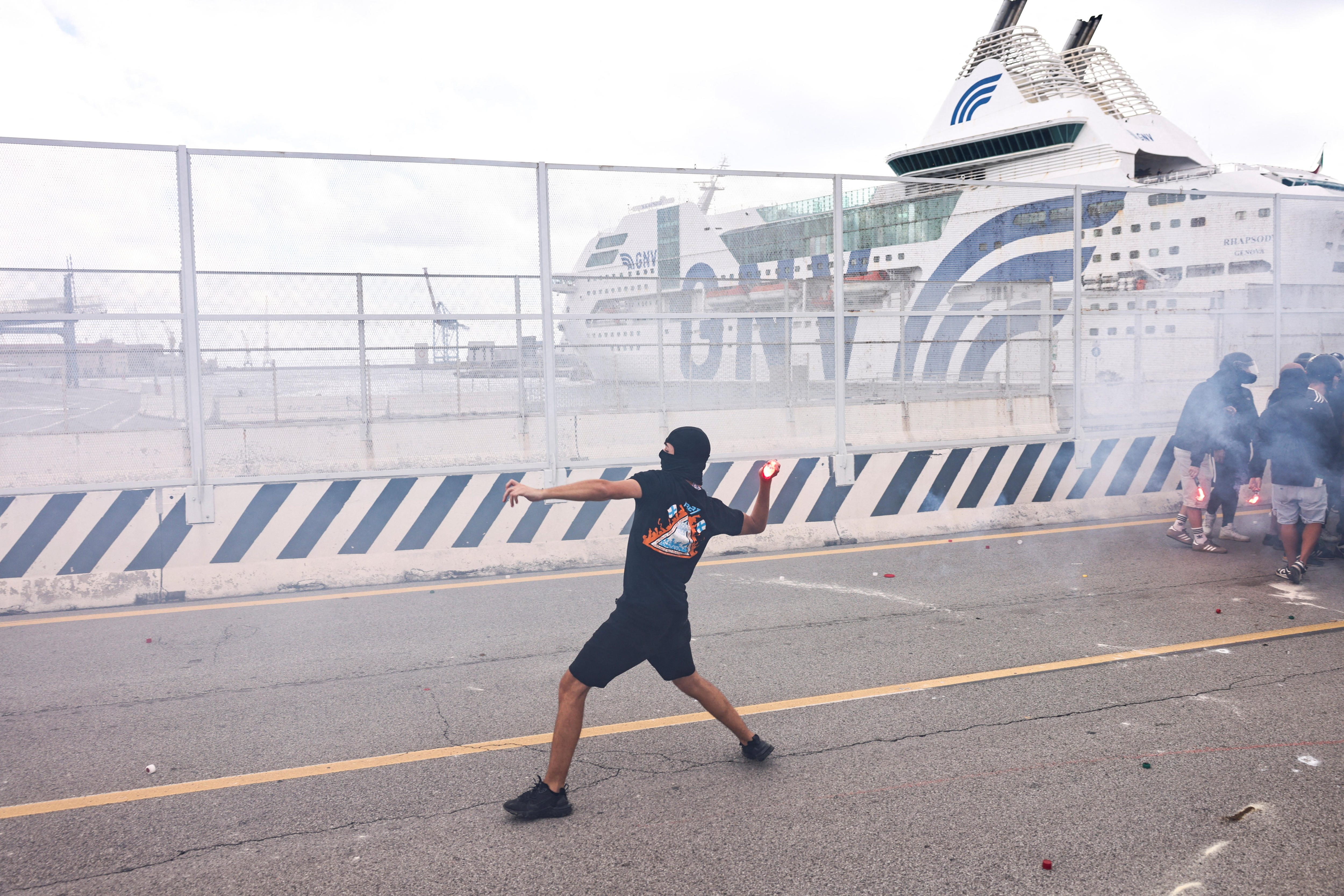 A protester out the front of a dockyard throwing an object.