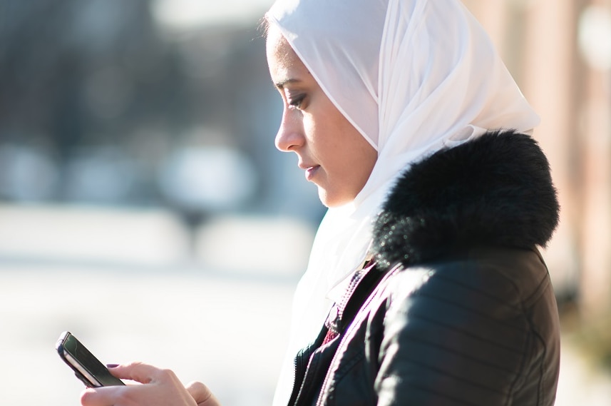 Migrant woman checks  phone for COVID information