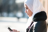 Migrant woman checks  phone for COVID information