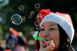 A woman dressed as Santa blows bubbles