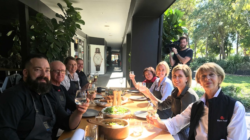 People sitting around a table with their glasses raised