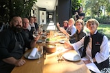 People sitting around a table with their glasses raised