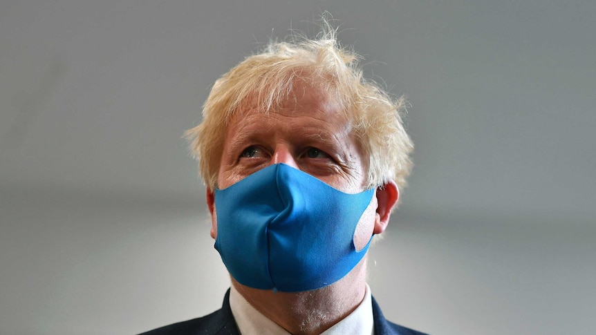 Britain's Prime Minister Boris Johnson wears a blue face mask.