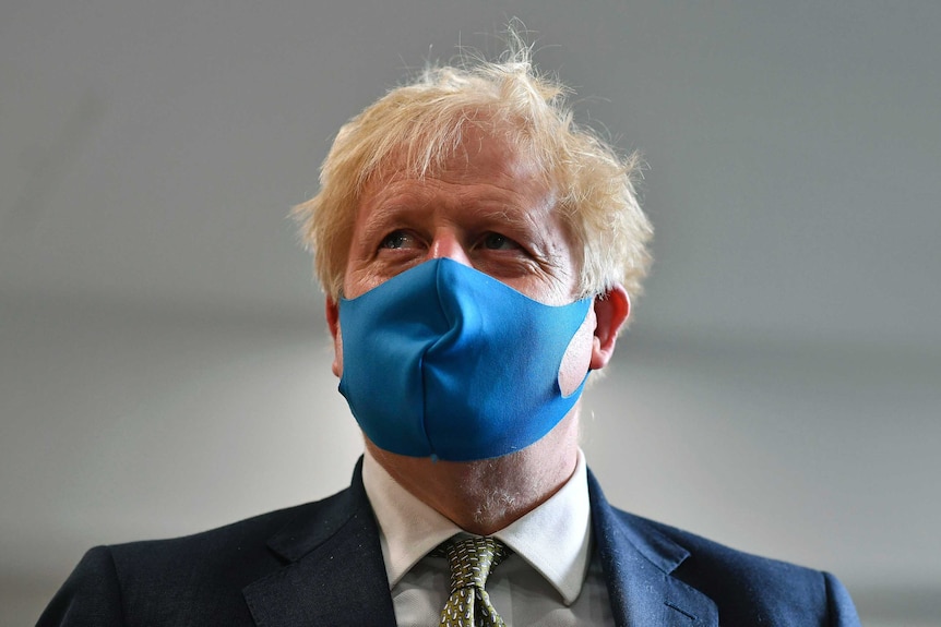 Britain's Prime Minister Boris Johnson wears a blue face mask.