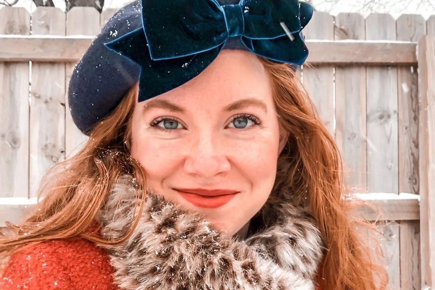 Danielle stands in the snow wearing a hat.