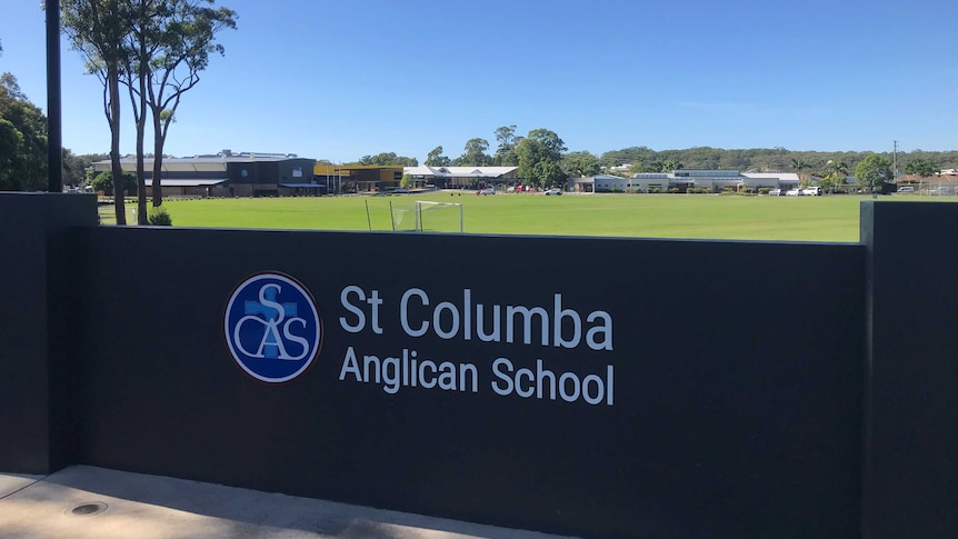 Image of the St Columba Anglican School sign with the school and oval visible in the background