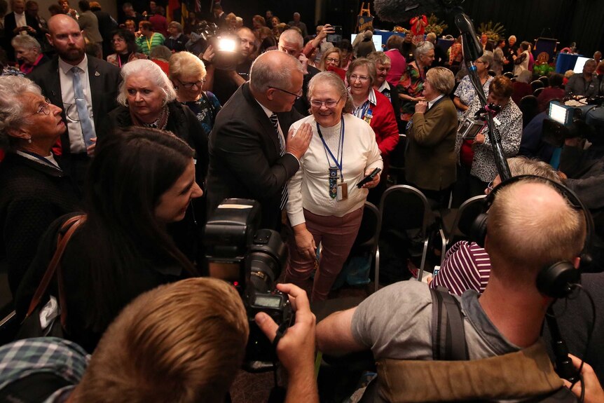 Scott Morrison and a lady who'd been knocked over stand together in the middle of a crowd of women