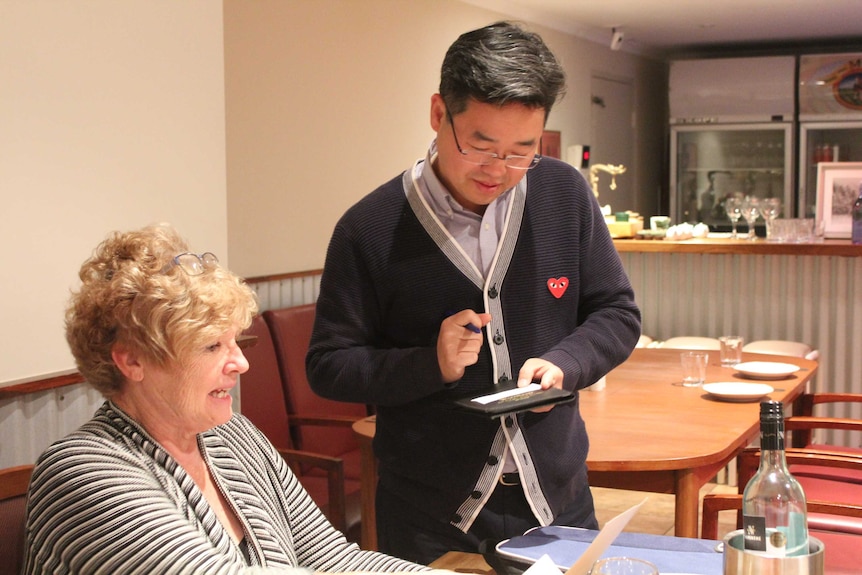 Stephen Kim takes an order in his outback restaurant.