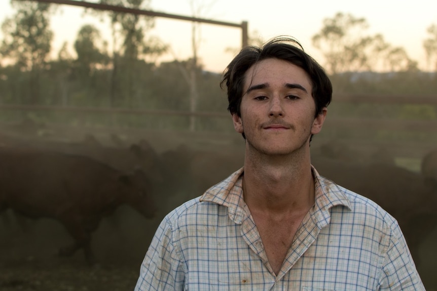 A man in a dusty stockyard.