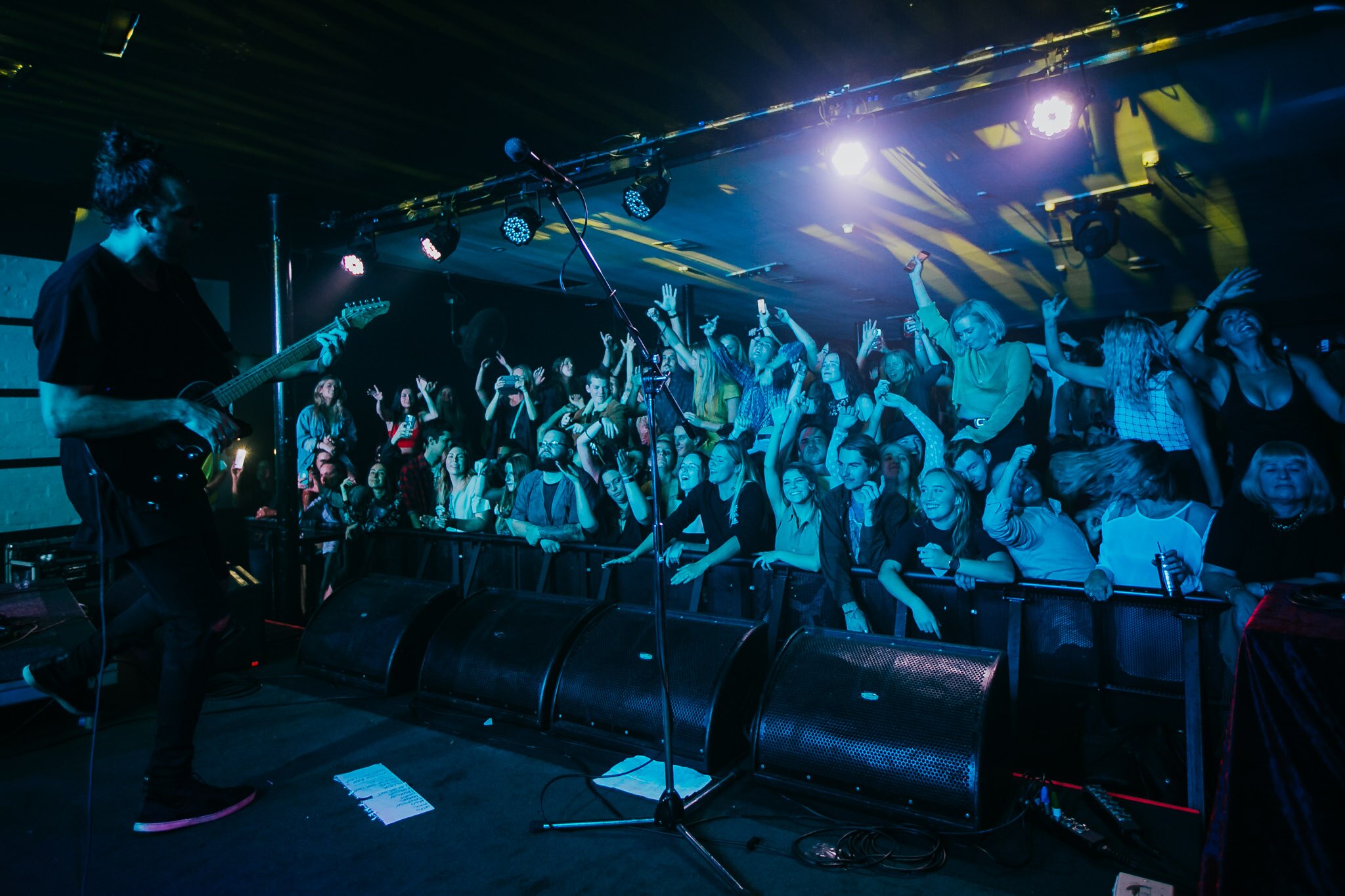 A packed front row audience enjoys a guitarist performing live on stage