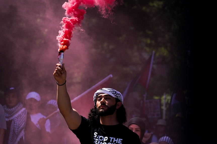 A young man holds a flare at Sydney pro-Palestinian rally