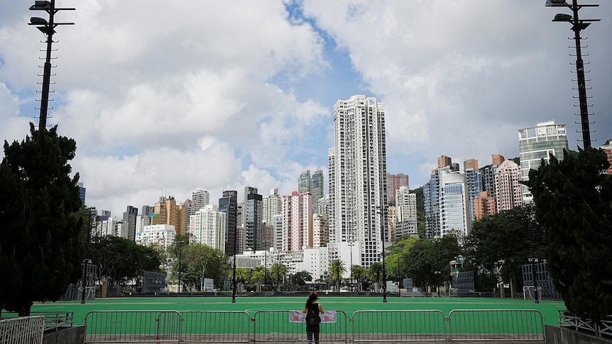 A woman stands in front of the closed Victoria Park in Hong Kong.