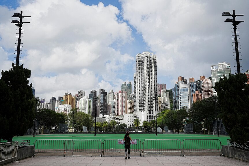 A woman stands in front of the closed Victoria Park in Hong Kong.