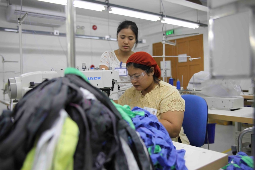 Worker sews while supervisor watches