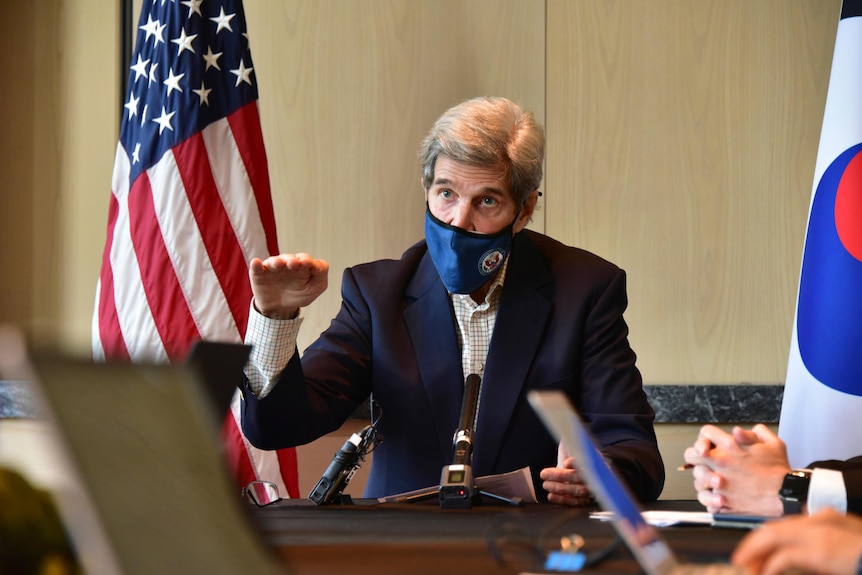 US special envoy John Kerry gestures while wearing a face mask