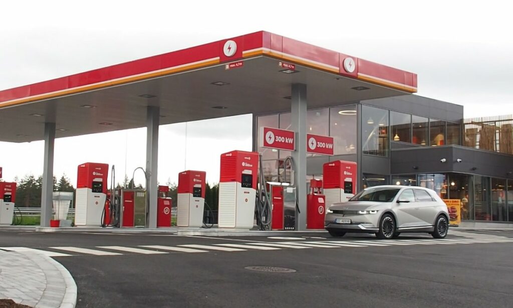 Six EV chargers at a fuel station with a sign reading 300kW