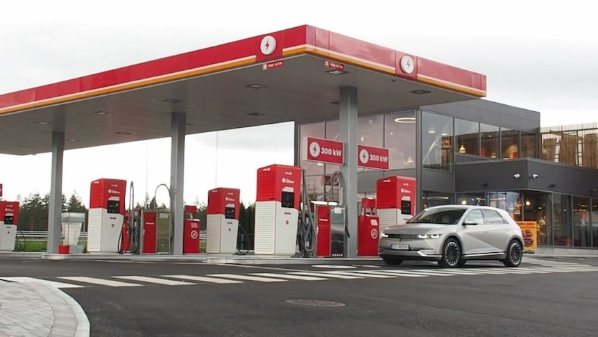 Six EV chargers at a fuel station with a sign reading 300kW