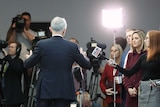 Malcolm Turnbull stands with his back to the camera. He is facing a large media pack with lights, cameras and microphones.