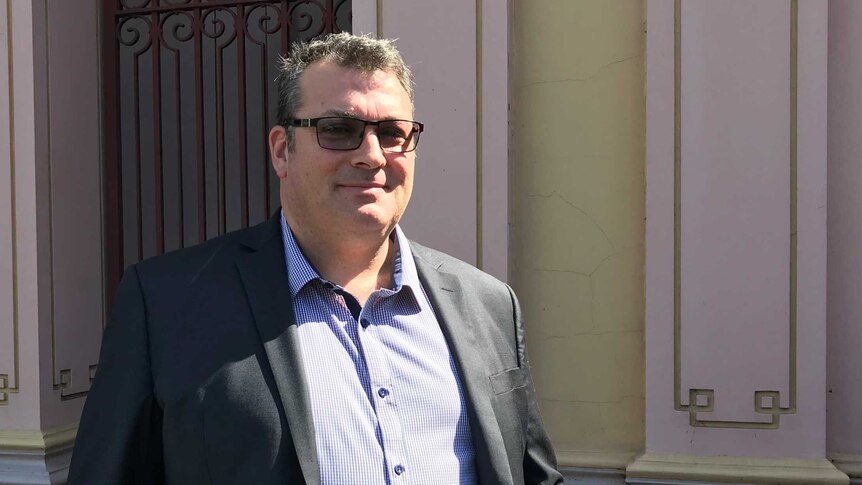 A man in a suit and sunglasses leaving a courthouse.