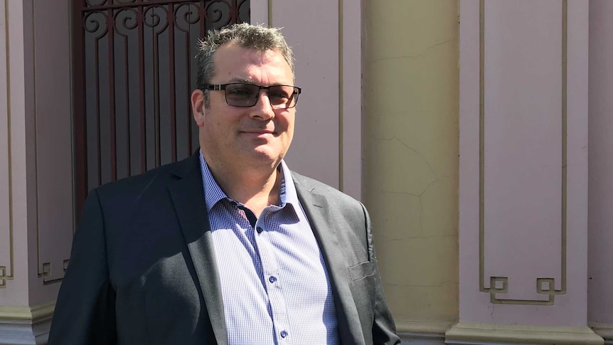 A man in a suit and sunglasses leaving a courthouse.