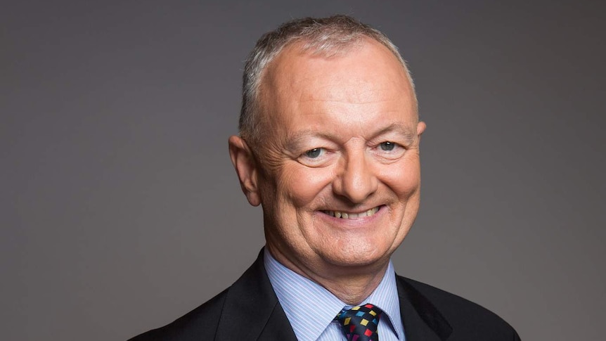 ABC election expert Antony Green smiles at the camera with his hands clasped behind his back.