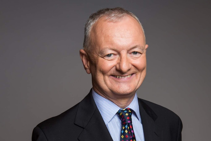 ABC election expert Antony Green smiles at the camera with his hands clasped behind his back.