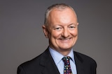 Antony Green smiles for the camera with his hands clasped behind his back.