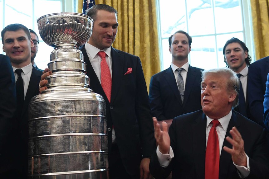 Alexander Ovechkin grips the Stanley Cup while listening to Donald Trump in in the Oval Office.