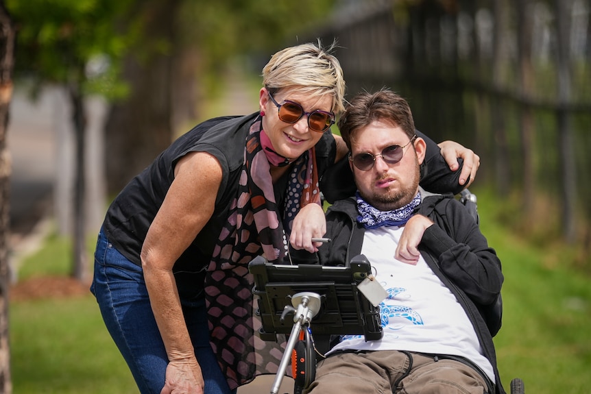 A middle-aged white woman and her adult son, who lives with intellectual disability hugging on a footpath