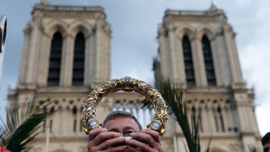 French Archbishop Patrick Chauvet holds the Holy Crown of Thorns aloft with Notre Dame in the background