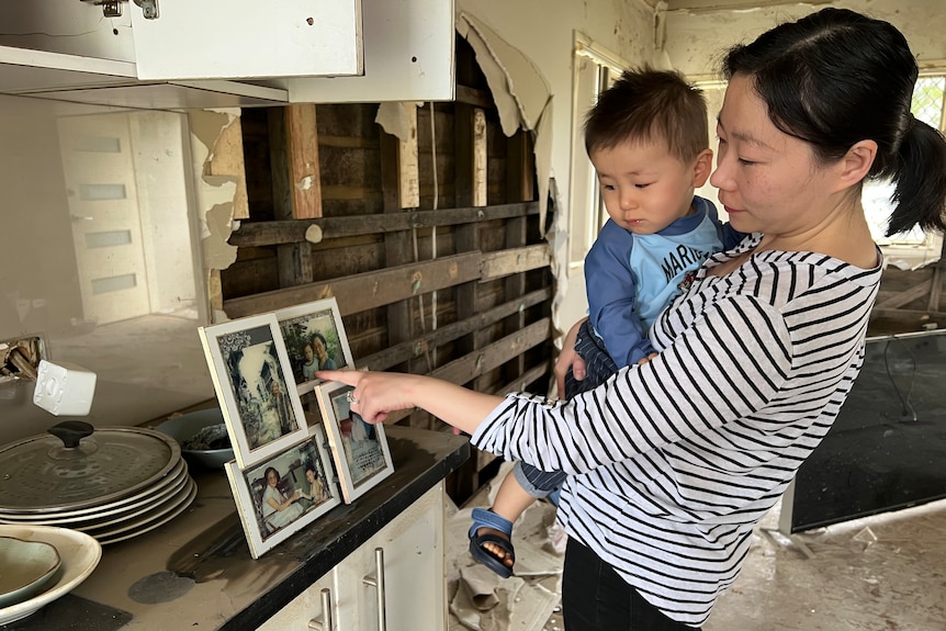 Sandy Xia and son Nulan look at old photos in their flood damaged home.