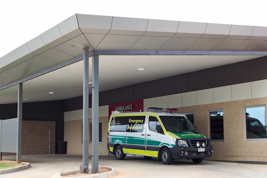 An ambulance parked under a shelter at a hospital
