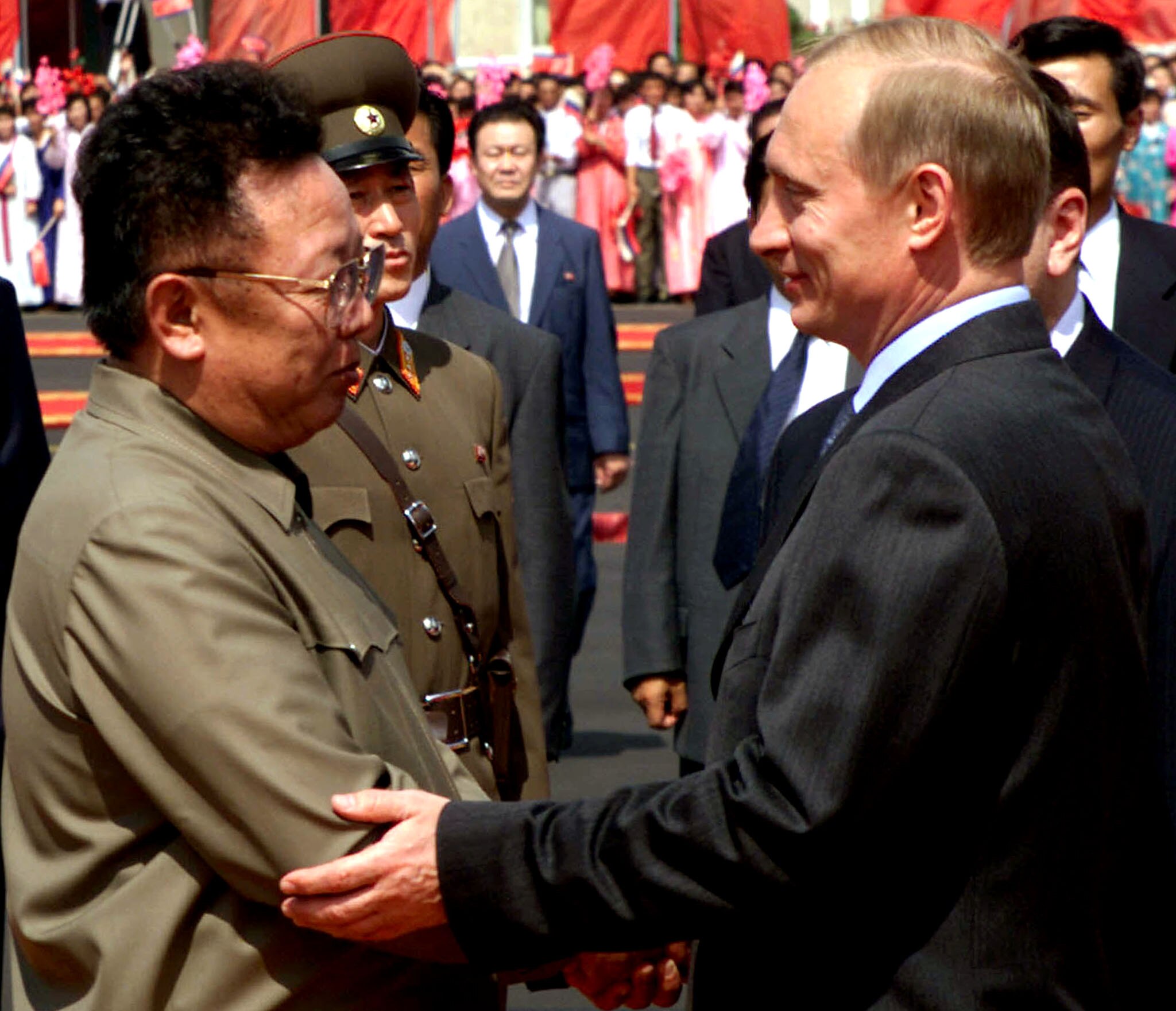  Kim Jong-il stands opposite Vladimir Putin while the pair shake hands.