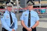 Two police officers in uniform stand in front of the surfers paradise sign