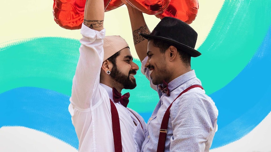 Two men looking lovingly at each other and holding red balloons.