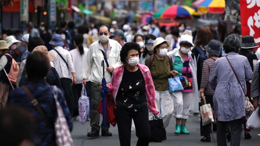 A street is crowded by shoppers wearing face masks