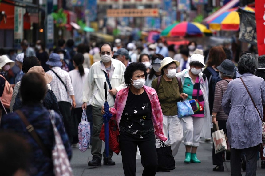 A street is crowded by shoppers wearing face masks