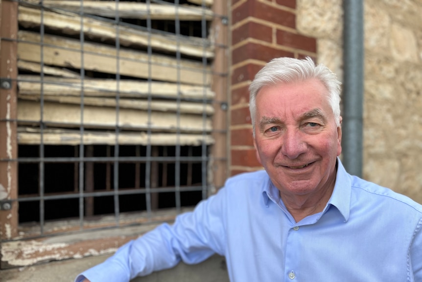 A man leans on the window sill of an old building 