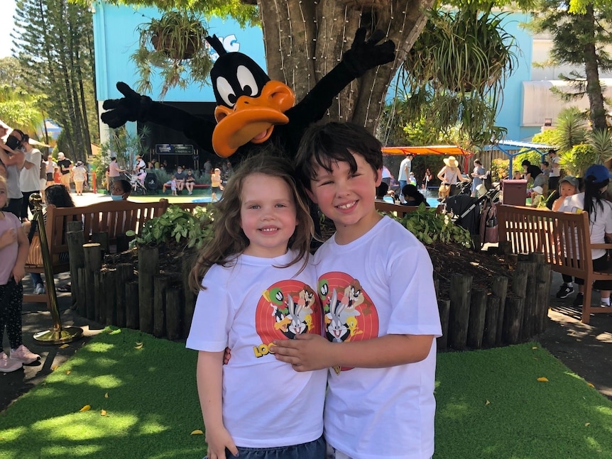 Alice Salisbury and her brother stand arm in arm in front of Daffy Duck. 