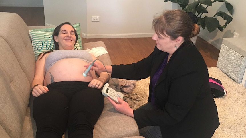 Midwife Sonya Beutel with patient Krystal Kleidon in the living room of a home or office.