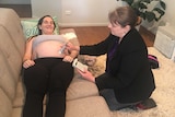 Midwife Sonya Beutel with patient Krystal Kleidon in the living room of a home or office.