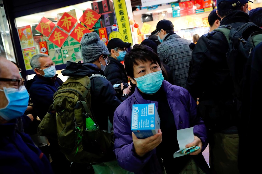 A person wearing a mask queuing among other people wearing marks