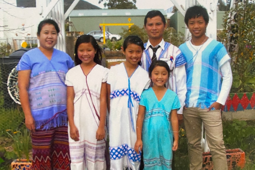 old picture of a family standing together in front of a community garden wearing bright blue coloured clothes
