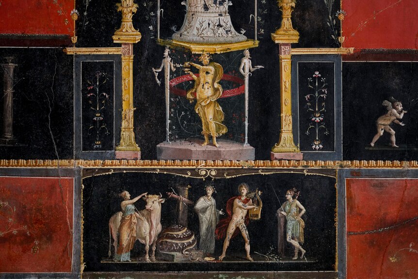 A detail of a roman mural featuring a gold woman stnading between two pillars. 