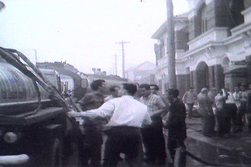 B&W Still from archival vision 1967 bushfires men in office clothes hauling out firefighting hose
